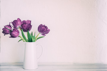 Fresh pink tulip flowers bouquet on shelf in front of stone wall. View with copy space