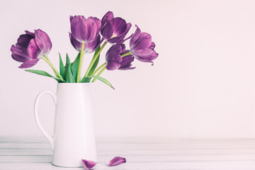Fresh pink tulip flowers bouquet on shelf in front of stone wall. View with copy space