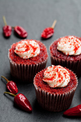 Chocolate  cupcakes with red hot chili pepper on black stone background