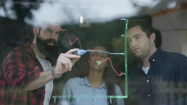  Young professional team in business startup drawing graph on window