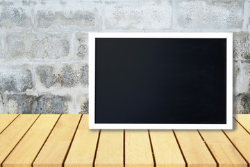 Blank black chalkboard lean on wooden table and old gray concrete wall,  Blank copyspace for your text or design.