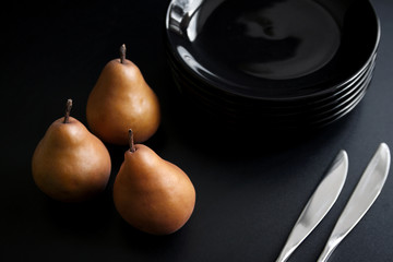 Brown pears and black plates