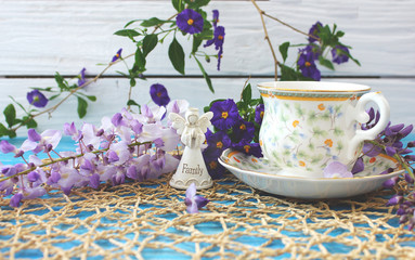 A cup of tea on a wooden blue table with a bouquet of colored field flowers