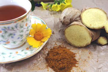 A cup of tea on a table with ginger and ground turmeric. Concept of health.