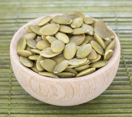 Full bowl of pumpkin seeds close up on a wooden table