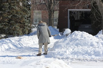 Man shoveling snow from his driveway after a heavy snowfall.   