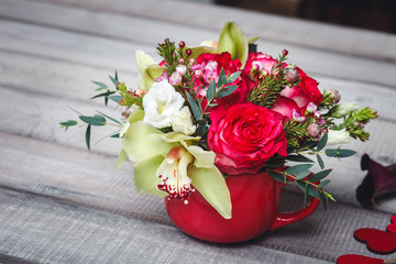 Small red vase with bouquet of flowers and Lilies on wooden table space for text