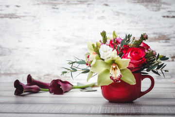 Small red vase with bouquet of flowers and Lilies on wooden table space for text