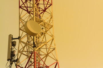 Mobile phone communication antenna tower with satellite dish on blue sky background