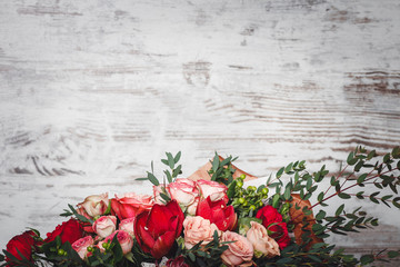 Many roses and flowers lie on the background of a wooden wall