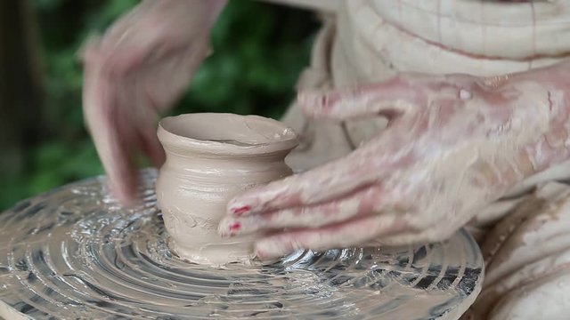 Man and woman makes a pot on pottery wheel. Hands of a potter and his apprentice. Woman is the pupil of a potter. Man and woman hands
