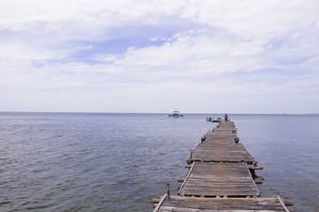 Blue sea with ship and wooden pier landscape. Romantic seaside view toned photo.