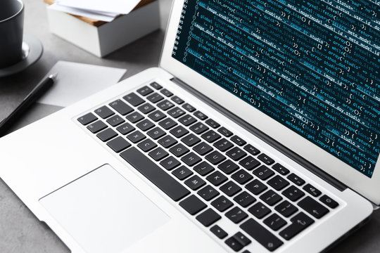 Laptop of programmer with script code on display