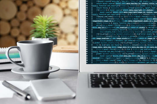 Laptop of programmer with script code on display