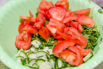 Salad in a bowl. Cut tomato, cucumber, greens. Healthy food, home cuisine.
