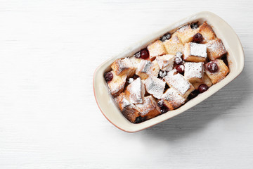 Freshly baked bread pudding in casserole dish on wooden table