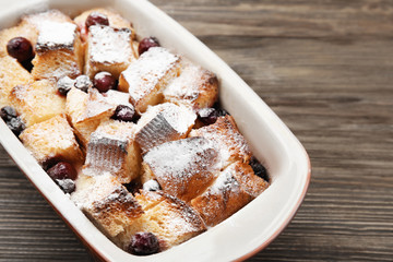 Freshly baked bread pudding in casserole dish on wooden table