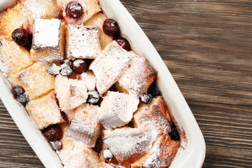 Freshly baked bread pudding in casserole dish on wooden table