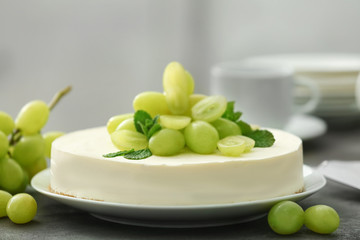 Delicious cheesecake with grapes on table