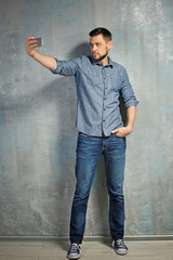 Obraz premium Young man taking selfie while standing near textured wall