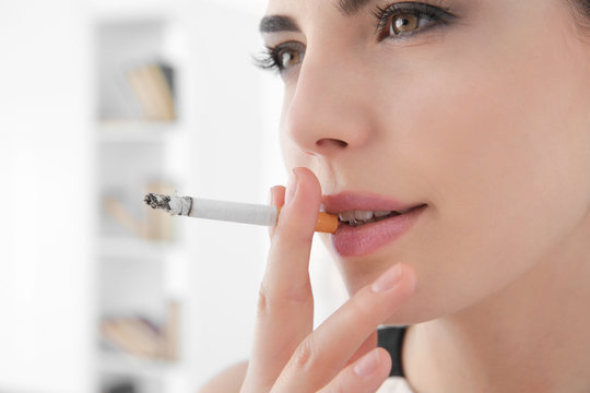 Young woman smoking cigarette at home