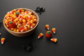 Bowl with tasty Halloween candies on dark background