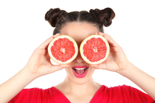 Beautiful young woman with grapefruit halves near eyes on white background