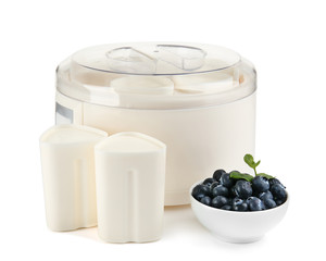 Modern yogurt maker and bowl with berries on white background