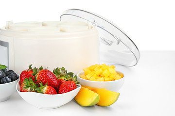 Modern yogurt maker and ingredients on white background