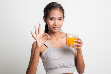 Young Asian woman drink orange juice show OK sign.