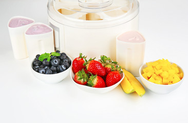 Modern yogurt maker and ingredients on white background