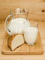 Piece of a white loaf and glassware filled with milk