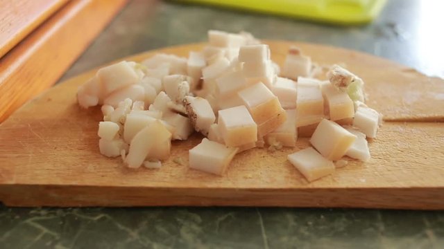 Cutting pork fat with a knife on a cutting board