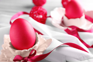 Composition of Easter egg in ceramic stand and ribbon on tablecloth