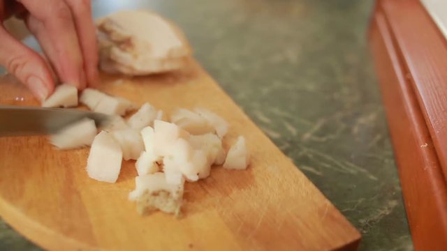 Cutting pork fat with a knife on a cutting board