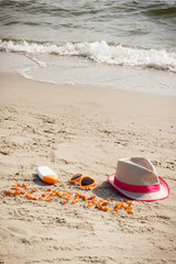 Fototapeta na wymiar Word summer, sunglasses, sun lotion and straw hat on sand at beach, summer time