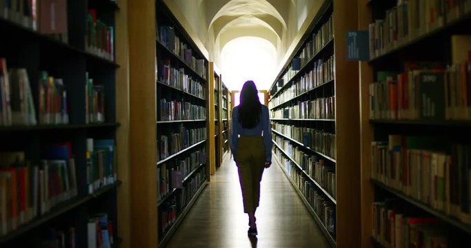 A beautiful young woman studying in a happy and carefree library reading the book. Concept: educational, portrait, library, and studious, relax.