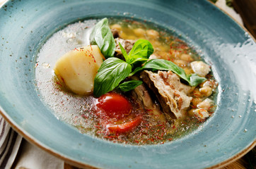 Soup with mutton broth with mutton meat, rice, chickpeas, potatoes, carrots, bell peppers, tomatoes, greens and oriental spices