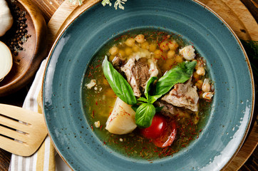 Soup with mutton broth with mutton meat, rice, chickpeas, potatoes, carrots, bell peppers, tomatoes, greens and oriental spices