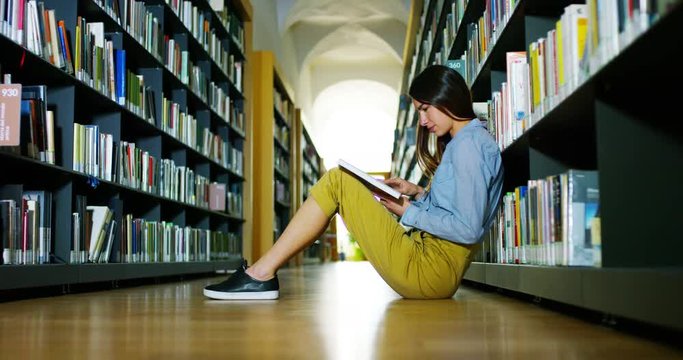 A beautiful young woman studying in a happy and carefree library reading the book. Concept: educational, portrait, library, and studious, relax.