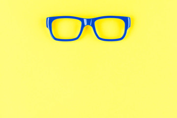 Blue eye glasses on yellow background. Advertising area concept