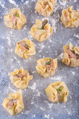 Uncooked shrimp and pork wontons on a flour dusted surface 