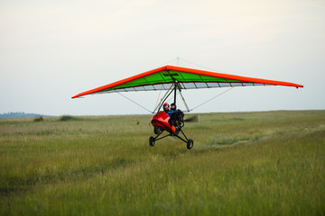 Obraz na płótnie Canvas Hang glider takes off from the grassy field.