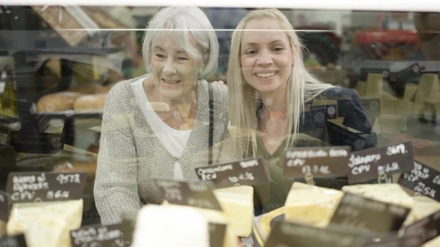  Senior lady & adult granddaughter shopping at deli counter in supermarket
