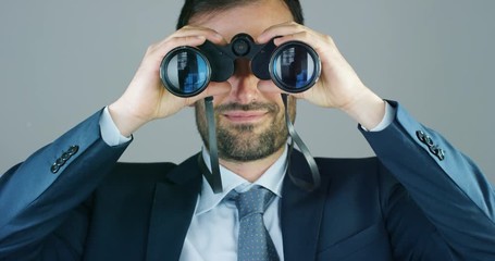 A businessman in a suit and tie, use the binoculars to look away with the concept of looking to the future, forecasting the economic and financial growth and the future - Powered by Adobe