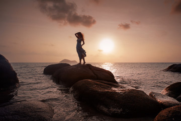 beautiful young woman silhoutte standing on stone at sunset - Powered by Adobe