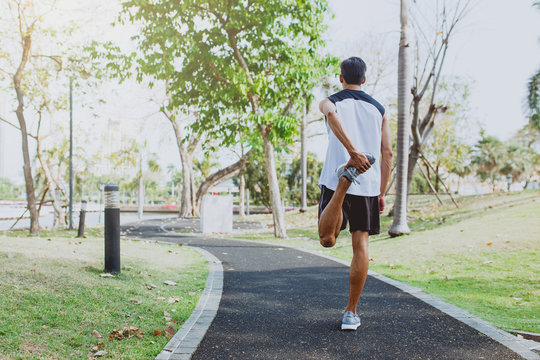 Young Man Stretching Bodies, Warming Up For Jogging In Public Park.