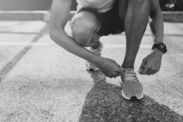 Runner trying running shoes getting ready for run. Black and white filter.