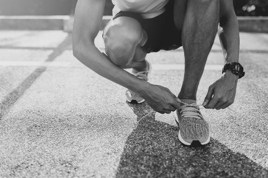 Runner trying running shoes getting ready for run. Black and white filter.