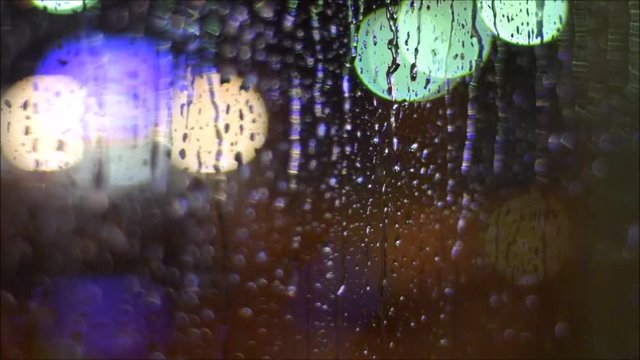 Regentropfen auf einem Fenster eines Lokals am Abend